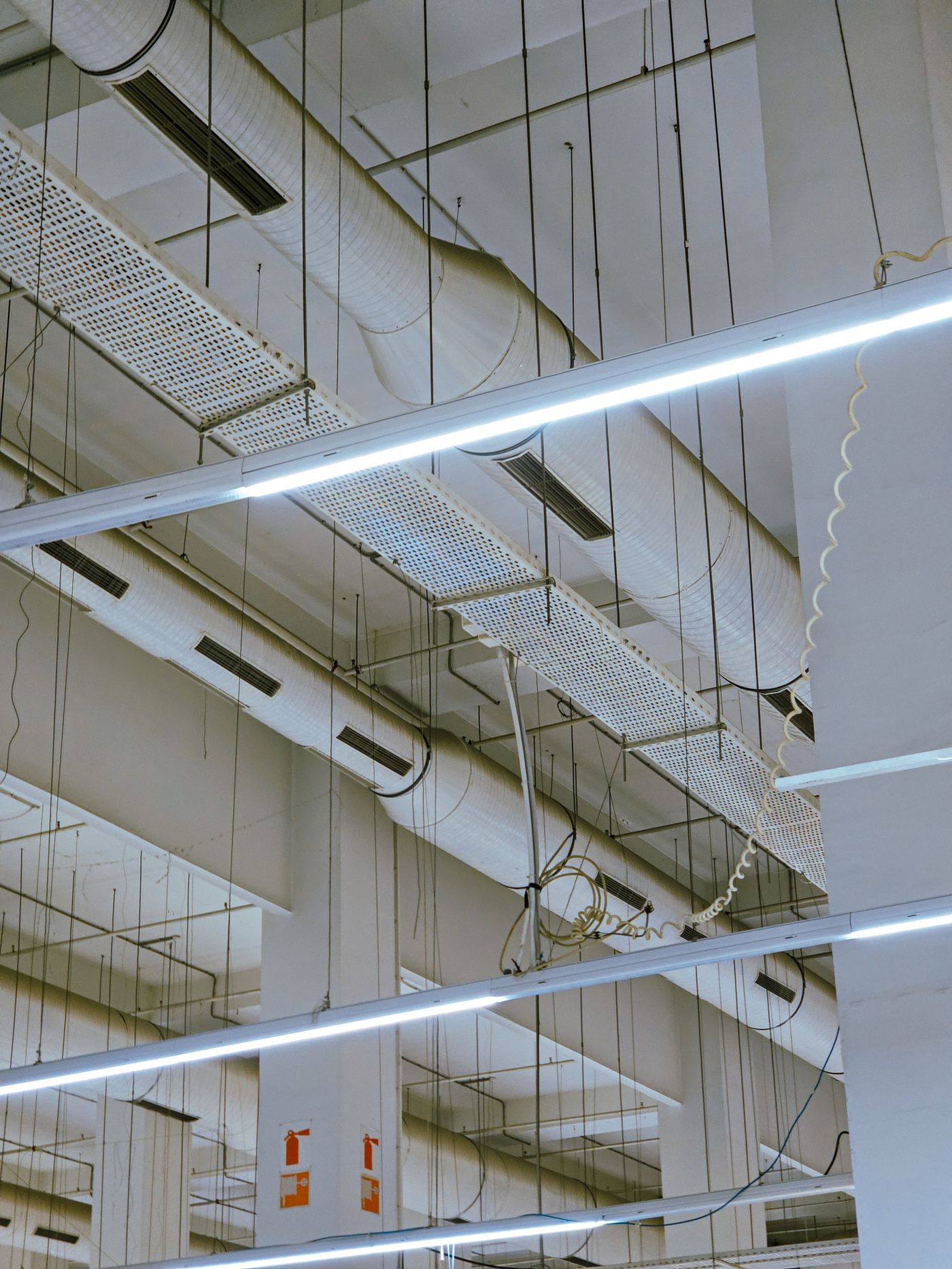 Overhead HVAC ductwork, cable tray, and lighting in a light commercial space