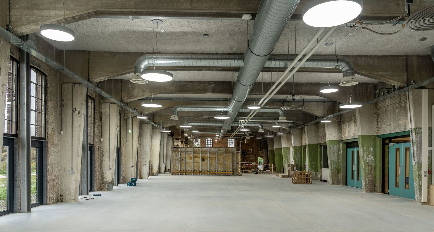 Open commercial interior with exposed spiral ductwork and suspended lighting