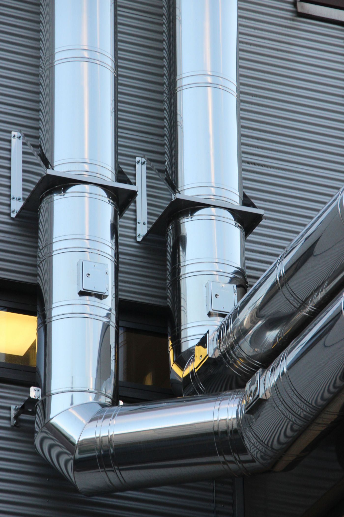 Stainless steel exhaust ductwork mounted on a commercial building exterior